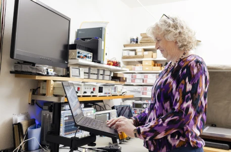 Martina Kreutz im EMV-Labor am Laptop. Im Hintergrund verschiedene EMV-Messgeräte