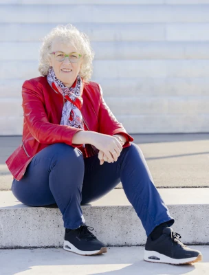 Martina Kreutz mit roter Lederjacke , auf Steintreppe sitzend